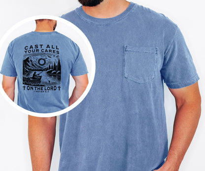 May include: A blue short-sleeved t-shirt with a pocket on the chest. The back of the shirt features a black and white graphic of a person fishing on a lake, with the text "CAST ALL YOUR CARES ON THE LORD" and a Bible verse reference.