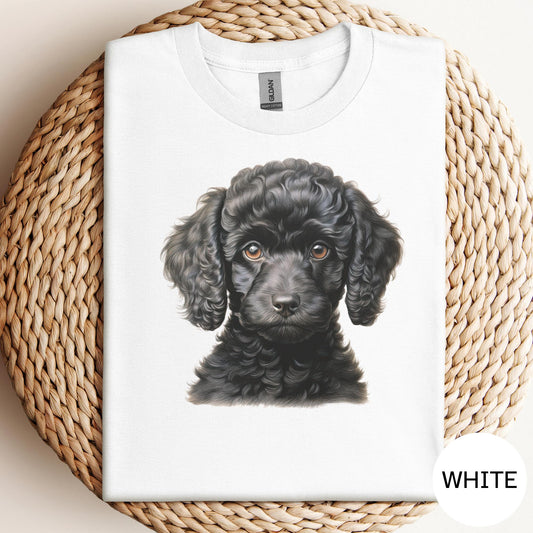 A white t-shirt with a black curly-haired dog printed on it, placed on a woven mat.