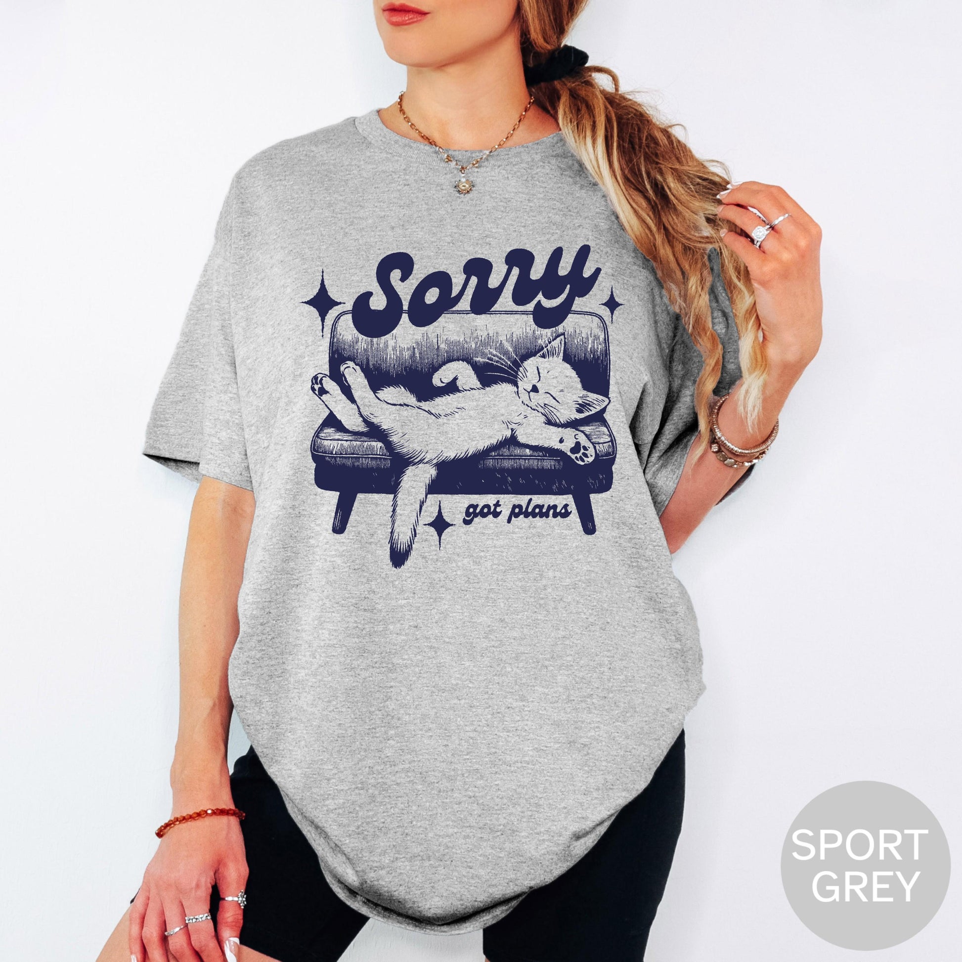 May include: Sport grey t-shirt with a graphic of a cat lounging on a couch. The text "Sorry got plans" is above and below the cat illustration. The cat is light grey and the couch is navy blue.