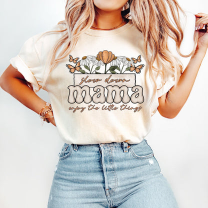 May include: A white t-shirt with a floral design and the text 'slow down mama enjoy the little things' in brown and orange lettering.
