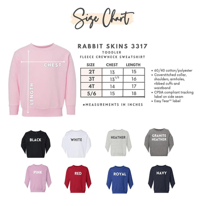 The image is a size chart for a rabbit skins toddler, specifically the 3317 size of a fleece crew neck sweatshirt. The chart provides measurements in inches for different age groups, including 2T, 3T, 4T, 5T, and 6T. It also displays the corresponding color options for each age group, such as black, white, gray, red, royal, and navy. The chart is accompanied by images of the sweatshirt in various colors, including pink, black, white, gray, red, royal, and navy.